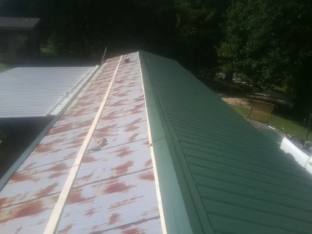 Old rusted panels beside newly installed green metal roofing — Wind Damage Roof Repair by Roofing Brothers in Mayer