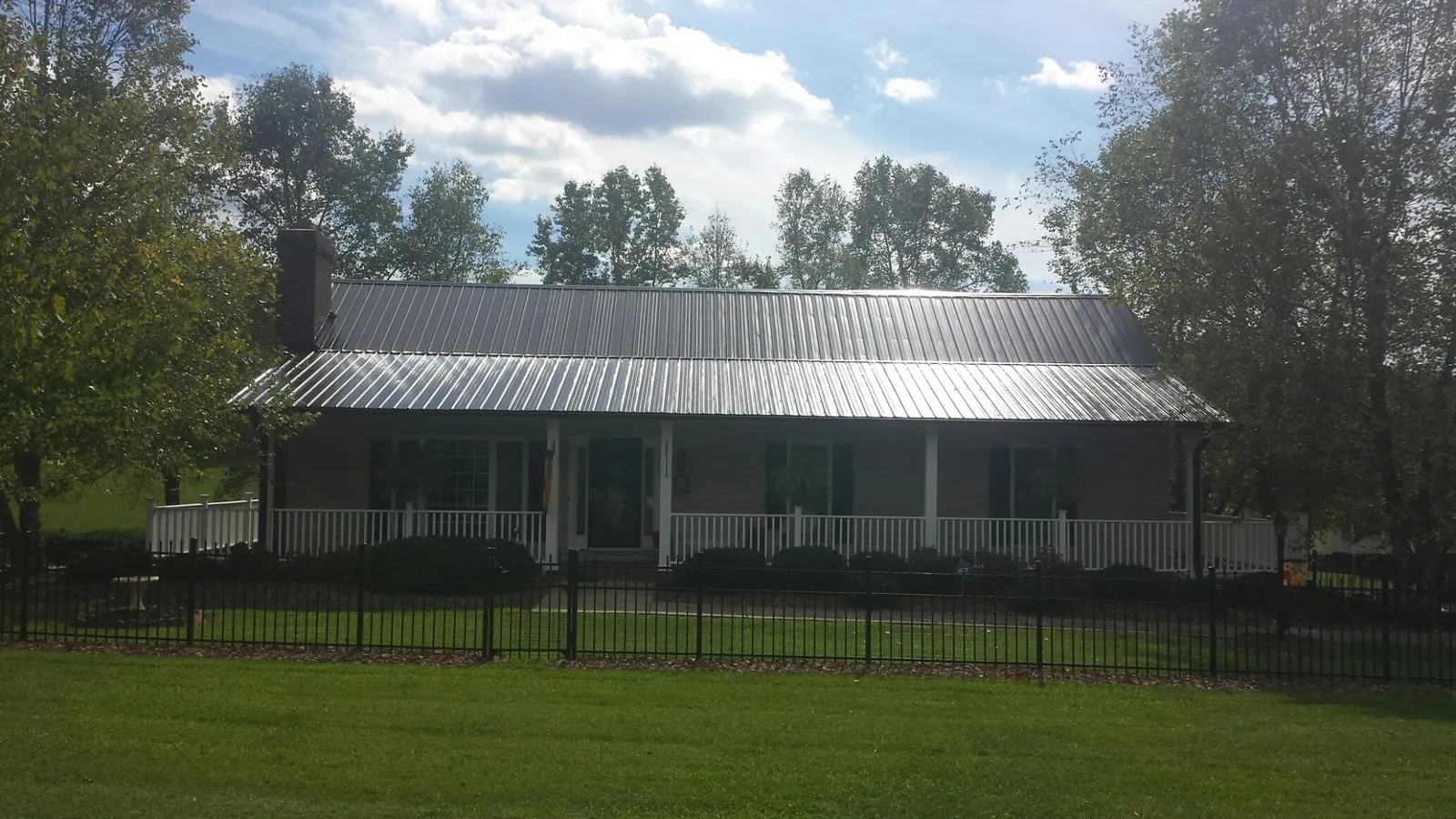 Gray metal roof on a brick ranch with a full width front porch — Gutter Guard Installation work by our crew in Mayer