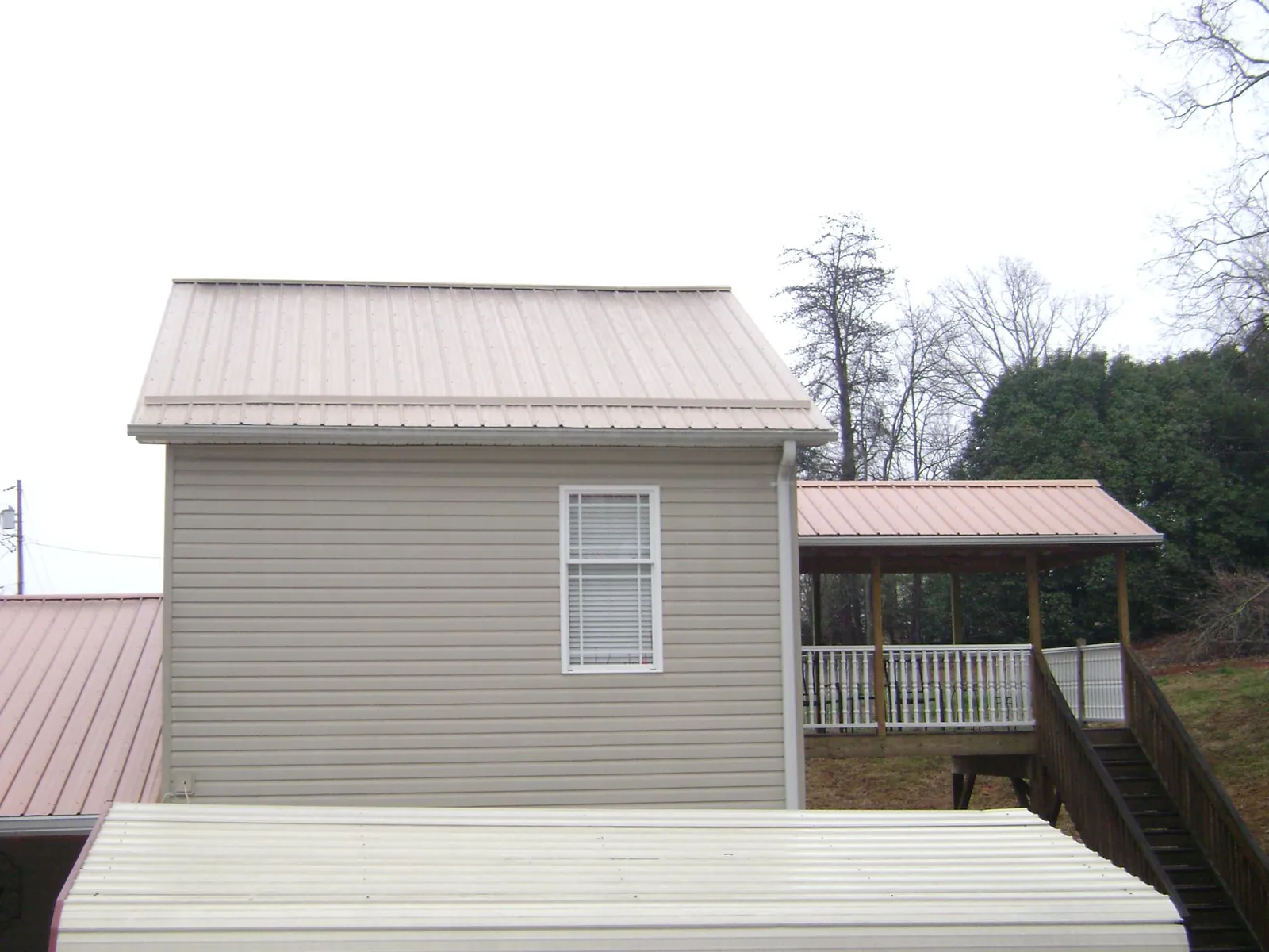 Tan metal roofs on a two story addition and attached porch, from a Roof Replacement job in Mayer