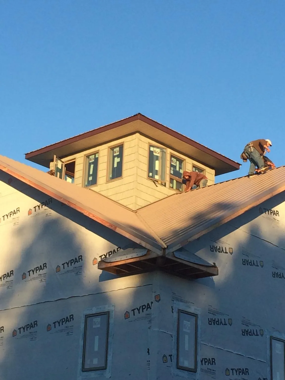 Roofers working around a rooftop cupola on a new metal roof at sunset — Roof Waterproofing in Mayer by Roofing Brothers